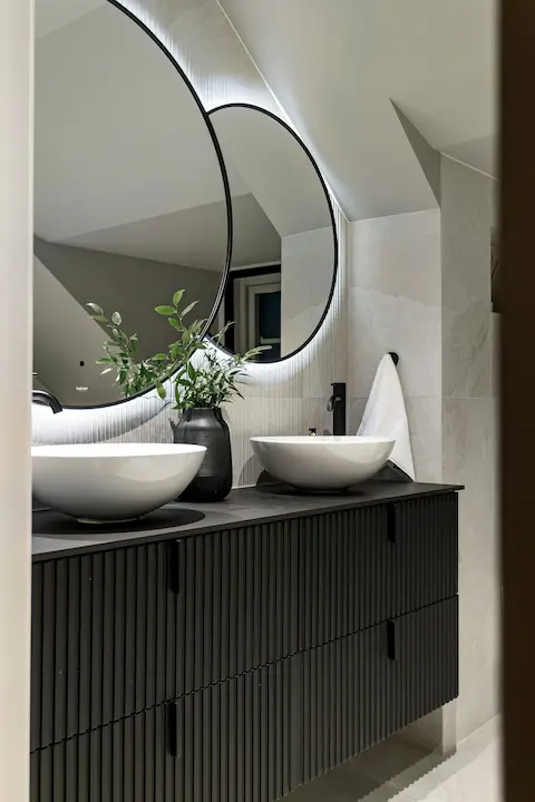Oversized round LED mirror above double sink vanity in modern bathroom
