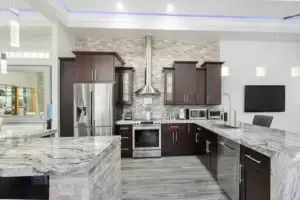 Stainless steel French door refrigerator in a modern white kitchen with marble countertop and smart appliance setup