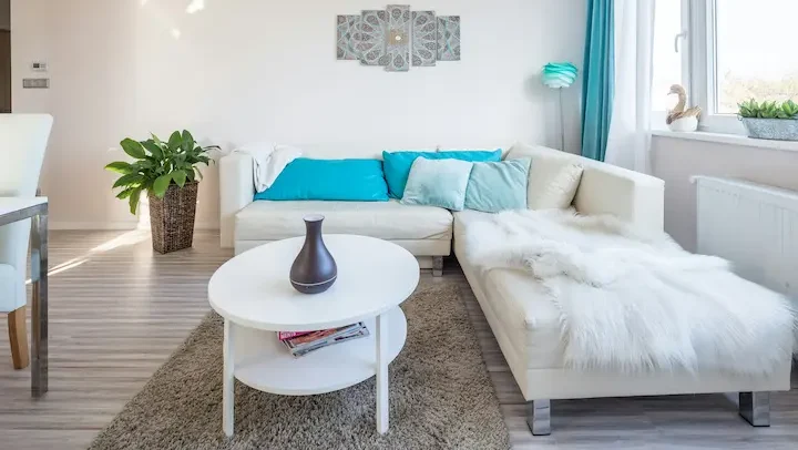 Minimalist white living room with floating media unit, wood flooring, and neutral-toned seating.