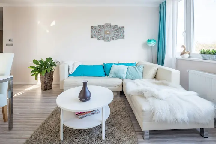 Minimalist white living room with floating media unit, wood flooring, and neutral-toned seating.