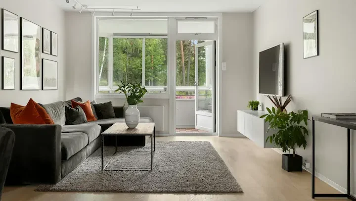 Contemporary living room with charcoal and beige palette, glass doors, and minimalist decor.