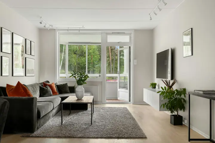 Contemporary living room with charcoal and beige palette, glass doors, and minimalist decor.