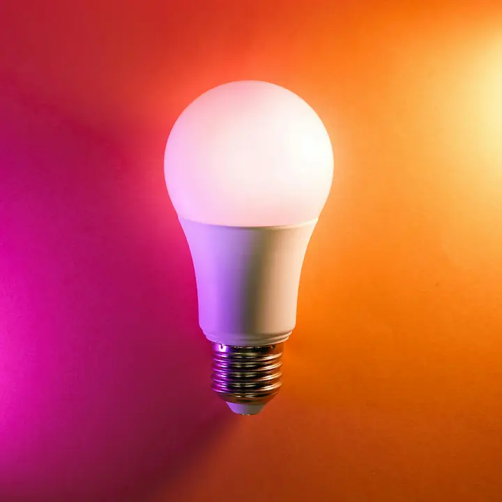 Stylish dimmable LED bulb glowing in orange and purple hues.