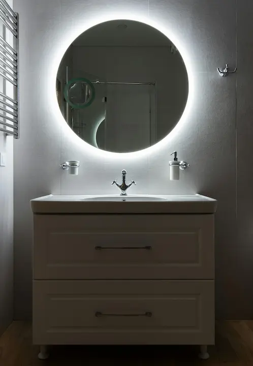 Circular LED mirror lighting in a bathroom setting.