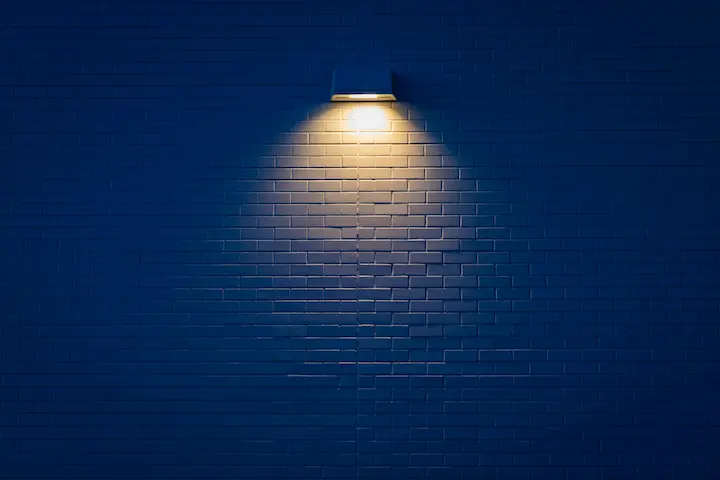LED wall-mounted light fixture casting warm beam on wall.