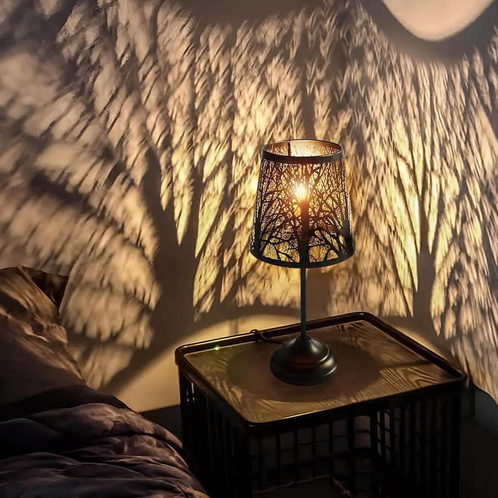 Perforated metal lamp casting intricate geometric shadow patterns on bedroom wall