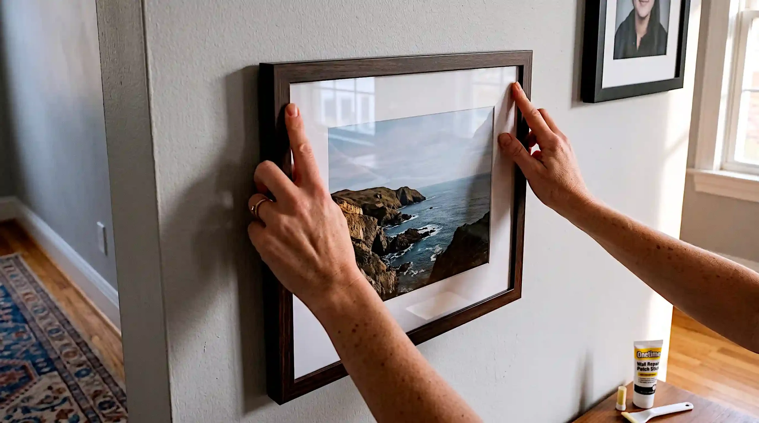 Pressing adhesive strip onto picture frame to test hold before hanging heavy art